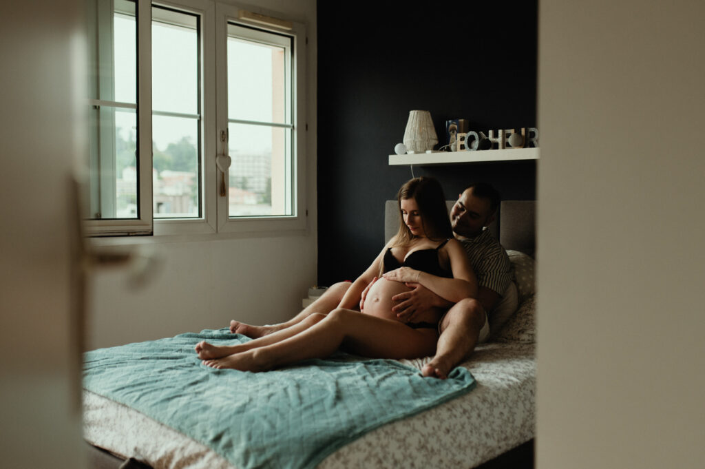 photographe grossesse saint etienne couple sur le lit regardant le ventre photographe grossesse saint etienne couple sur le lit